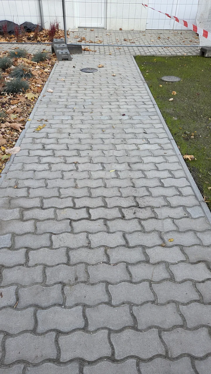 Szürke térköves járda füvesített sáv és ágyás mellett